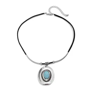 Close-up of vintage ethnic necklace with turquoise-set hat pendant on velvet cord.