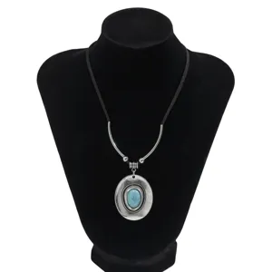 Close-up of vintage ethnic necklace with oval turquoise pendant and silver tube accents