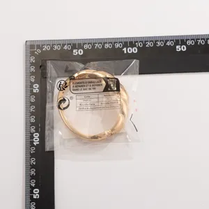Gepolijste goudkleurige druppelvormige armband met veerscharnier in winkelverpakking