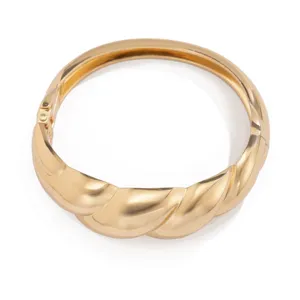 Detail van gepolijste gouden afwerking op een stijlvolle gedraaide veerarmband.