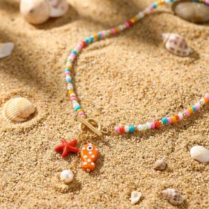 Detaillierte Nahaufnahme der bunten Perlenkette mit Fisch und Seestern auf Sand.