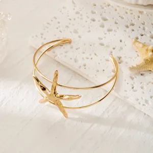 Dettaglio del bracciale da braccio a stella marina dorata su pietra bianca per stile da spiaggia