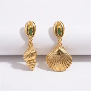 Detailansicht asymmetrischer goldener Ohrringe mit Muschel- und Schnecken-Motiv und grüner Einlage.