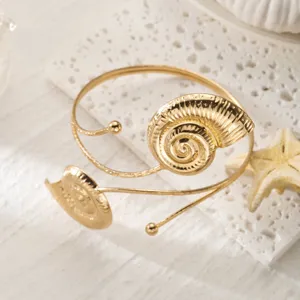 Vista dettagliata di un bracciale da braccio dorato regolabile con motivi a conchiglia.