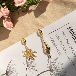 Detailansicht der goldfarbenen Ohrringe im Meeres-Design mit Schildkröte und Muschel