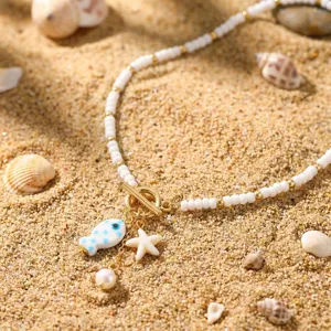 Nahaufnahme der böhmischen Sommerkette mit Keramikfisch- und Seesternanhängern auf Sand