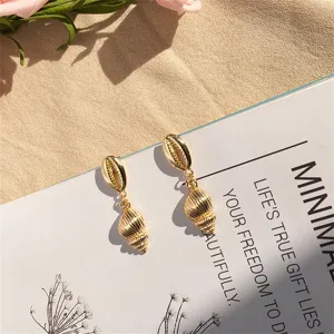 Detailansicht von goldenen Muschel- und Schnecken-Ohrringen für den Strandstil