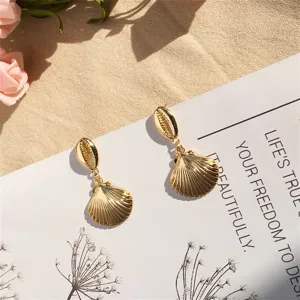 Detailaufnahme goldener Muschelohrringe mit filigranen Meeres- und Kauri-Strukturen