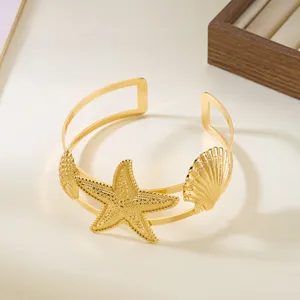 Dettaglio di un bracciale da braccio dorato regolabile con stella marina e conchiglie