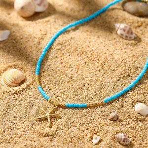 Nahaufnahme einer böhmischen blauen Perlenkette mit Seesternanhänger auf weißem Sand