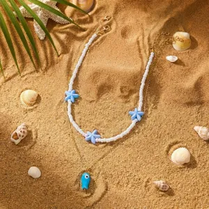 Detailansicht der böhmischen doppelten Halskette mit blauem Fisch und Seestern auf Sand.