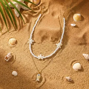 Detail einer böhmischen Lagenhalskette mit weißen Perlen und Seesternanhängern im Sand