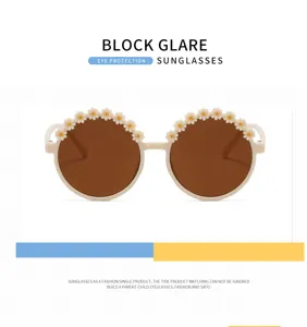 Close-up of children's round sunglasses featuring decorative daisy floral appliques.