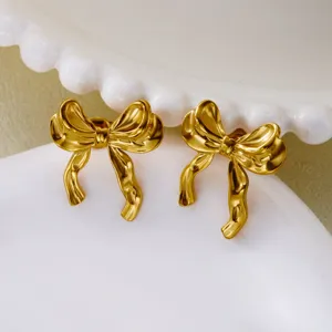 Close-up of elegant vintage gold bow earrings with textured metal finish on white plate