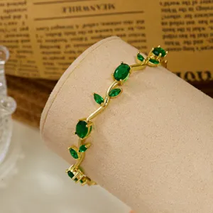Close-up of gold-plated vine leaf bangle with sparkling green crystal accents