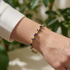 Close-up of gold-plated leaf vine bracelet with sparkling blue crystals