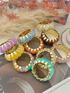 Dettaglio di bracciali elastici colorati in resina e oro su uno sfondo di rivista.