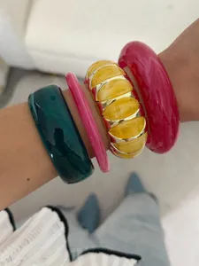 Primo piano di bracciali elastici in resina marmorizzata dai colori vivaci portati a pile