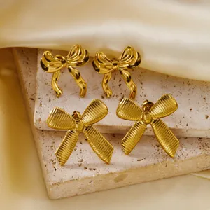 Elegant vintage gold bow earring set with smooth and textured finishes on stone slabs