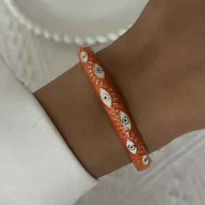 Elegant vintage orange enamel bangle bracelet featuring white evil eye pattern design