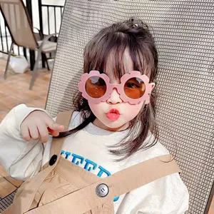Close-up portrait of a cute child wearing pink flower-shaped sunglasses for kids