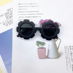 Close-up of matte black flower-shaped sunglasses for kids on a magazine page.