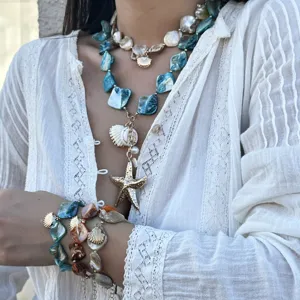 Nahaufnahme von Boho-Schmuck im Meeresstil mit Muscheln und Seestern auf Spitze.