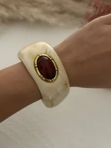 Detailansicht eines Vintage-Harzarmreifens mit Marmoreffekt und rotem Steininlay