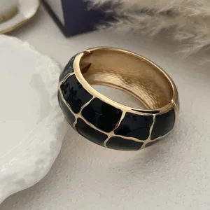 Detailweergave van een vintage goudkleurige armband met zwart emaille tegelpatroon