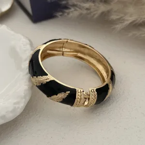 Detailopname van vintage zwarte emaille armband met gouden veren patronen