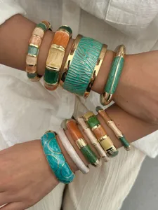 Close-up of stacked bohemian colorful enamel bangles featuring elegant gold-toned details.
