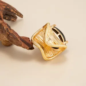 Detailed view of irregular golden ring with black resin inlay and textured finish