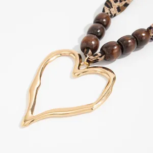 Macro view of a gold molten heart pendant on a leopard print silk scarf necklace