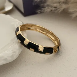 Gedetailleerde weergave van een vintage zwart emaille en goudkleurige luxe armband