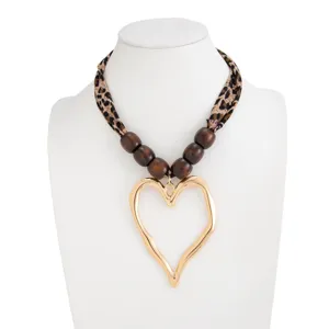 Detail of leopard print scarf necklace featuring golden lava style heart pendant on white bust