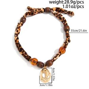 Detailed view of leopard print silk scarf necklace with gold lava heart pendant