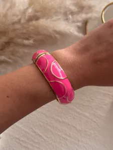 Vibrant rose pink enamel bangle featuring elegant gold-tone patterns, detail view