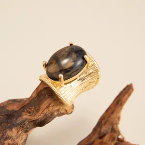 Detailed view of an irregular gold-finished ring featuring a large smoky resin stone.