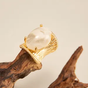 Detailed macro shot of an irregular gold-tone ring featuring a large cream resin cabochon