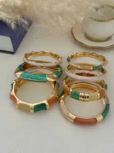 Detailed view of stacked colorful enamel Bohemian bangles on textured surface