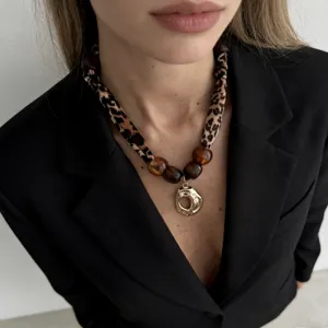 Detail of a Maillard style leopard print scarf necklace with golden molten pendant.