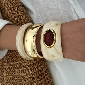 Set aus Vintage-Resin-Armreifen mit Goldmetall und rotem Steineinleger am Handgelenk