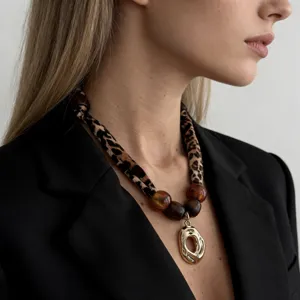 Detailed view of a leopard print scarf necklace with a golden molten metal pendant