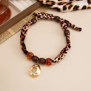 Macro detail view of vintage leopard print silk scarf necklace with organic gold lava pendant