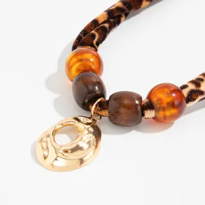 Detail of leopard print silk scarf necklace with amber beads and molten gold pendant
