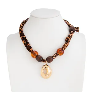 Detailed view of leopard print scarf necklace with golden lava pendant on white bust