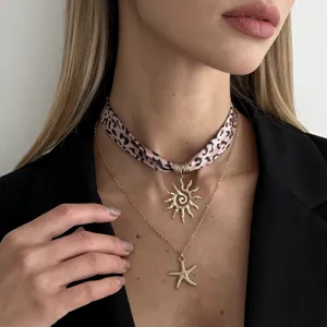 Close-up view of a layered leopard print scarf necklace with sun and starfish charms.