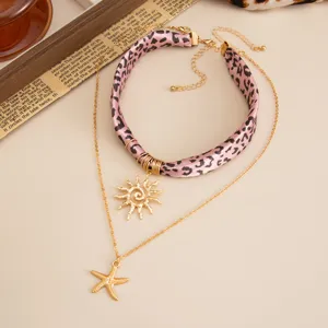 Detail view of layered pink leopard scarf necklace with golden sun and starfish pendants.