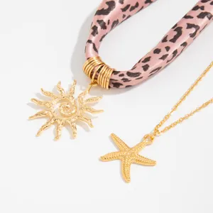 Detail view of golden sun and starfish pendants with leopard print scarf jewelry