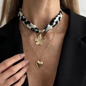 Macro view of vintage leopard print scarf necklace with metallic heart and flower pendants
